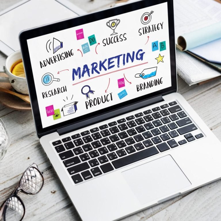 Notebook and laptop on a desk during marketing campaign planning