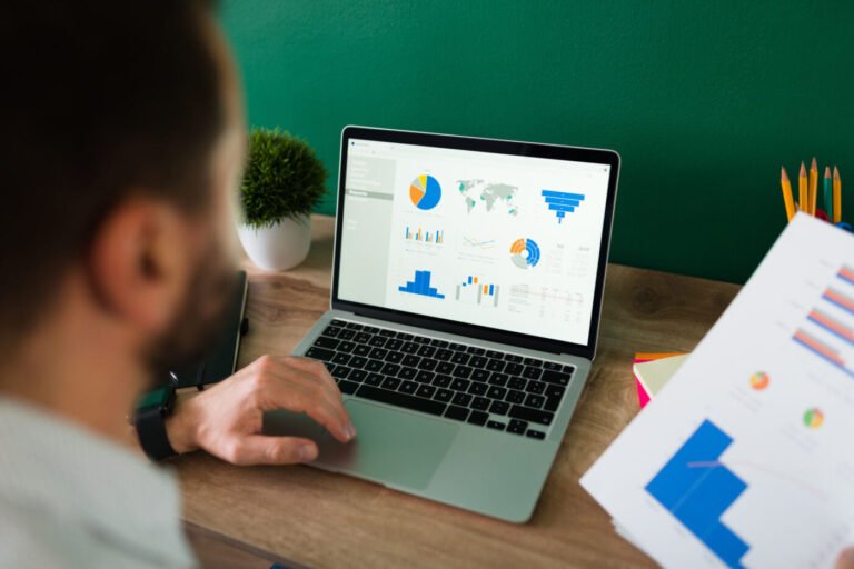 Young man at a laptop reviewing a work report and graphs
