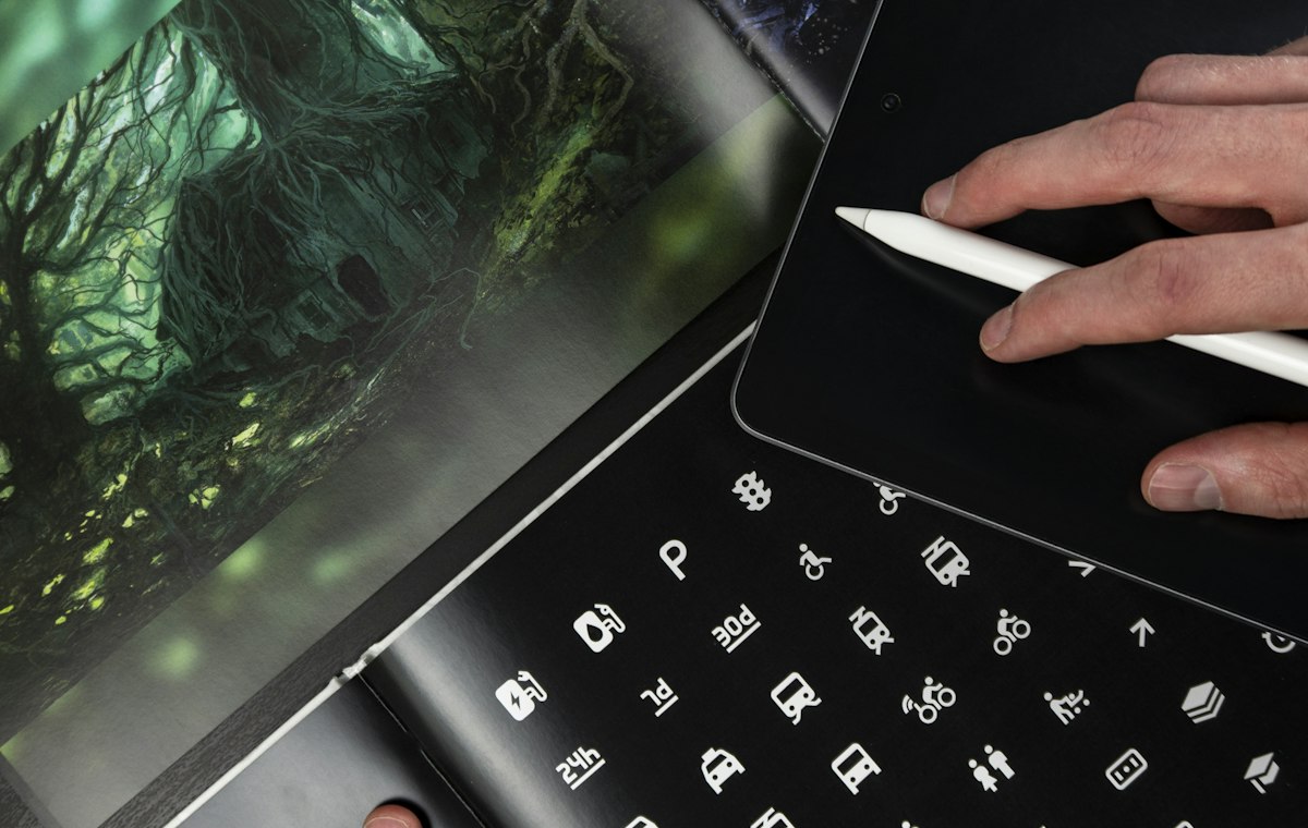 Printed design portfolio open next to a tablet and stylus